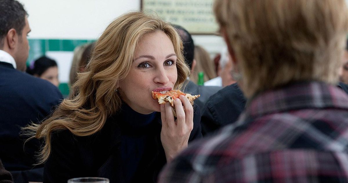 Elizabeth enjoys a pizza in Naples, Italy, savoring each bite with pleasure. This moment symbolizes her decision to embrace the simple pleasures of life while exploring Italian culture on her journey of self-discovery.